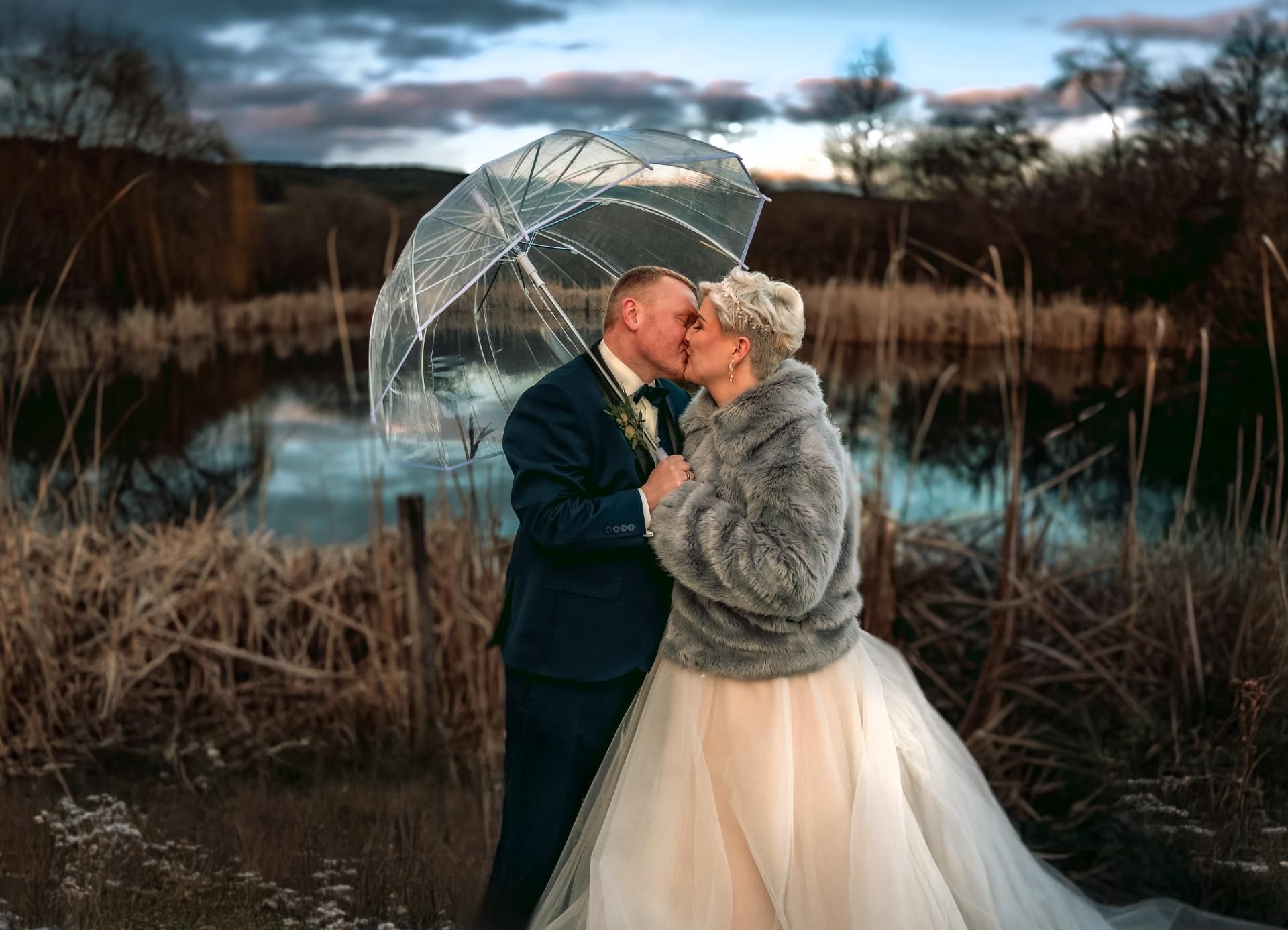 Hochzeitsfotografie – Brautpaar küsst sich unter einem transparenten Regenschirm