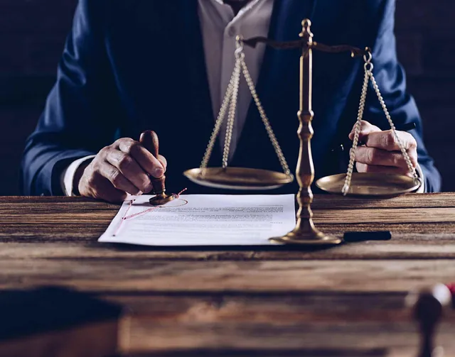 Un hombre con traje está sellando un documento con una balanza de justicia en el fondo.