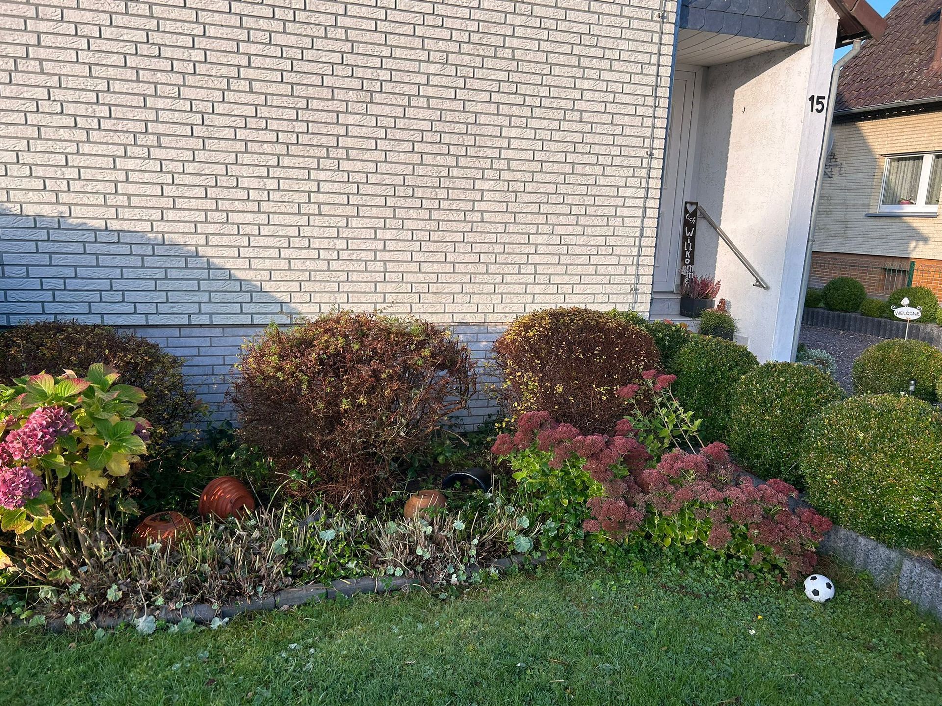 Ein weißes Backsteinhaus mit einem Garten davor