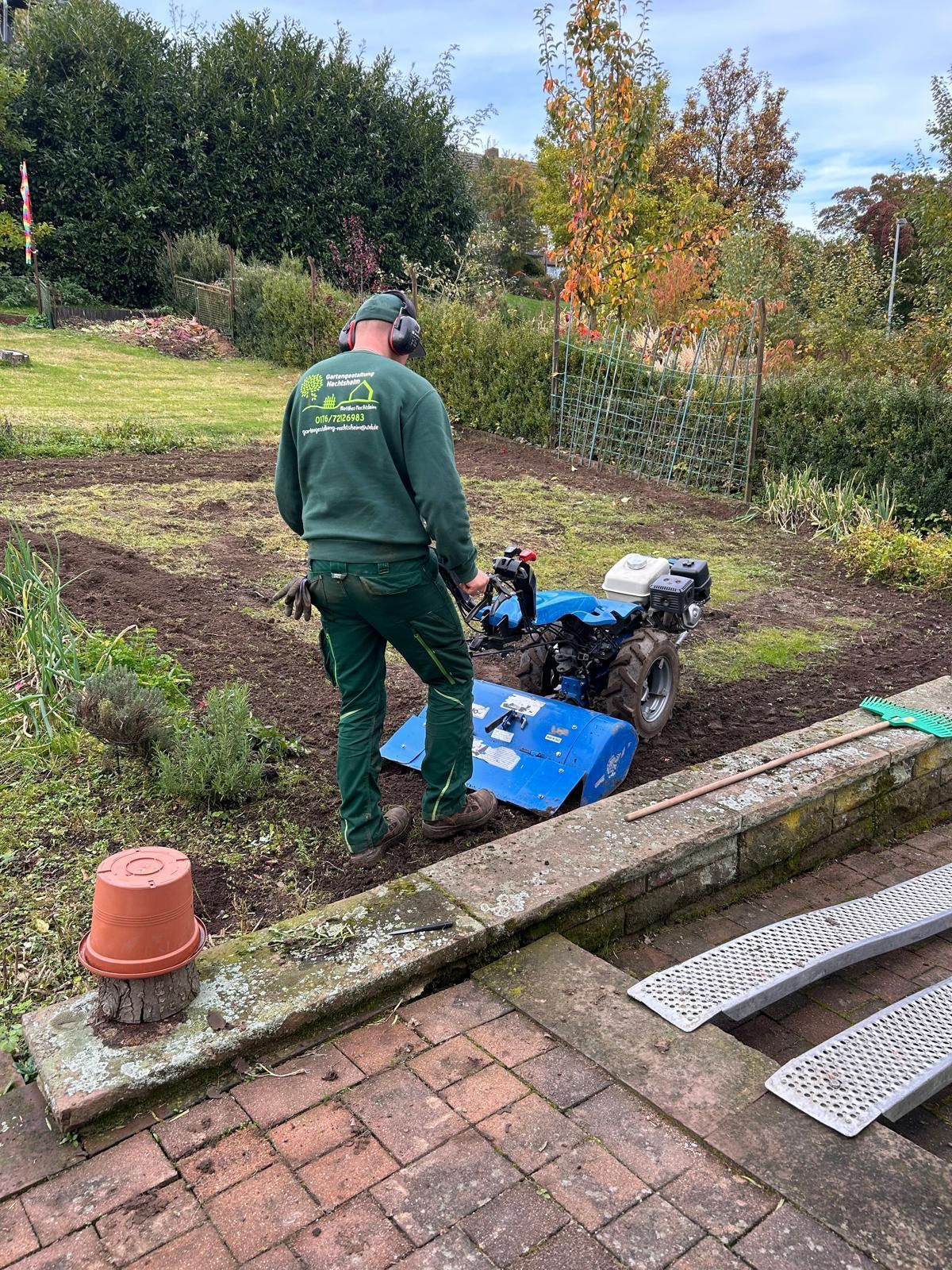 Ein Mann pflügt mit einem Traktor einen Garten.