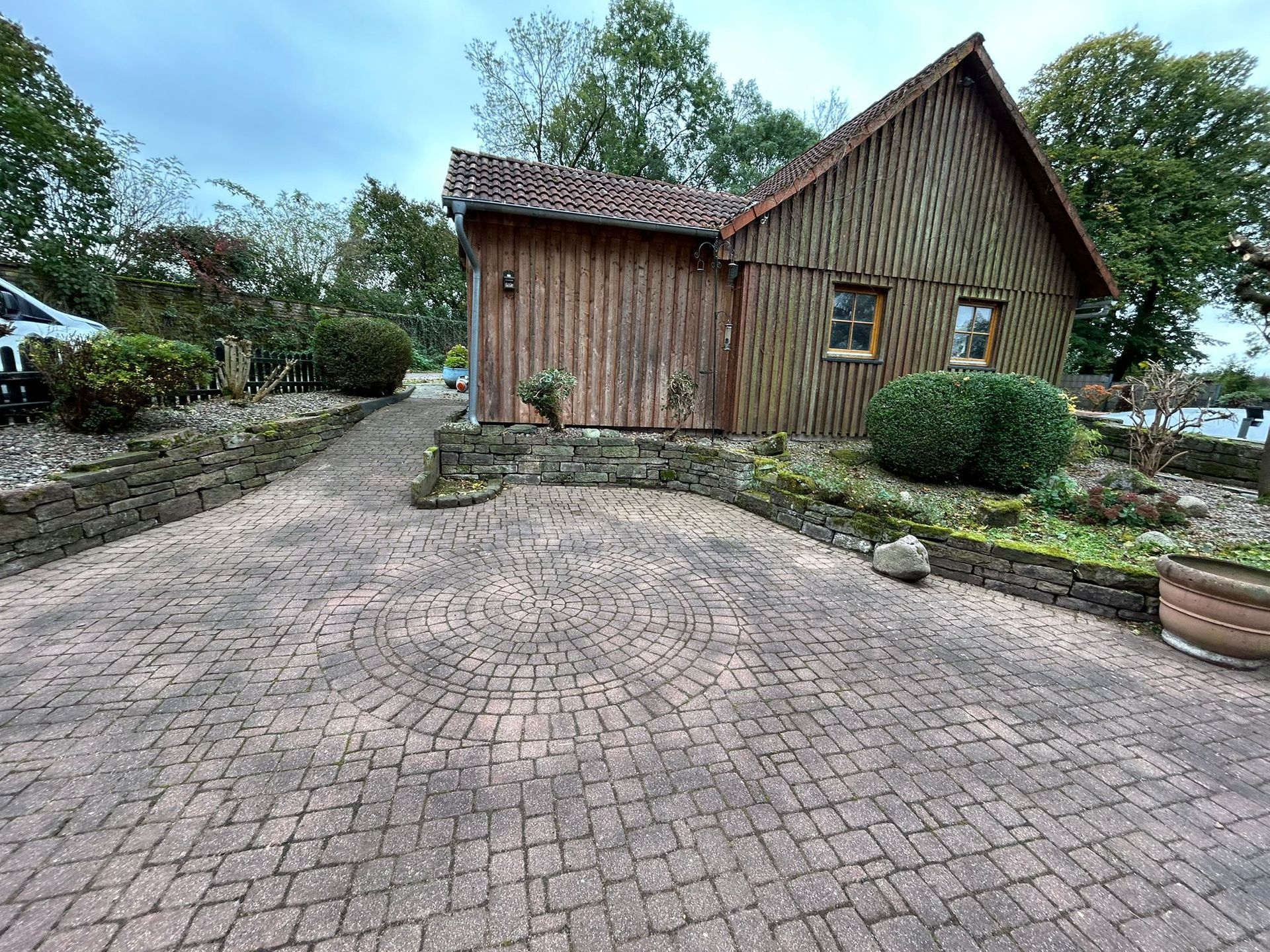 Es gibt eine gepflasterte Auffahrt, die zu einem Holzhaus führt.