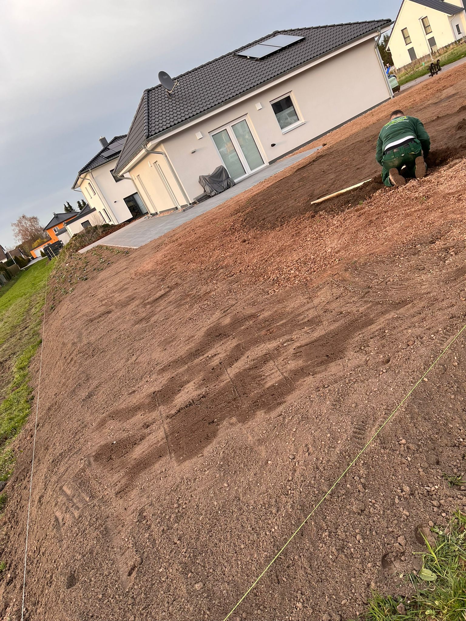 Ein Mann arbeitet auf einem Feld vor einem Haus.