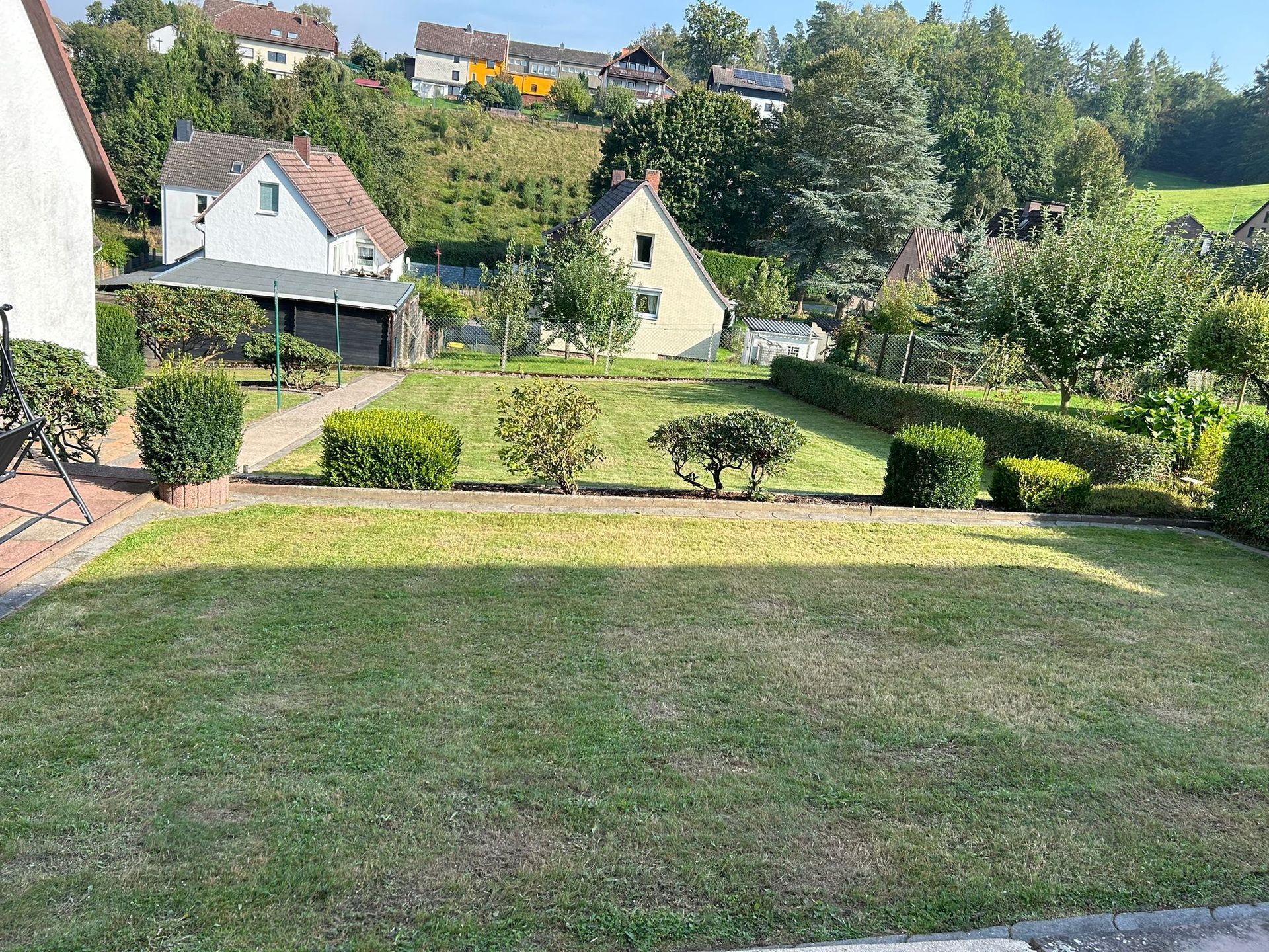 Ein großer, üppig grüner Rasen mit einem Haus im Hintergrund.