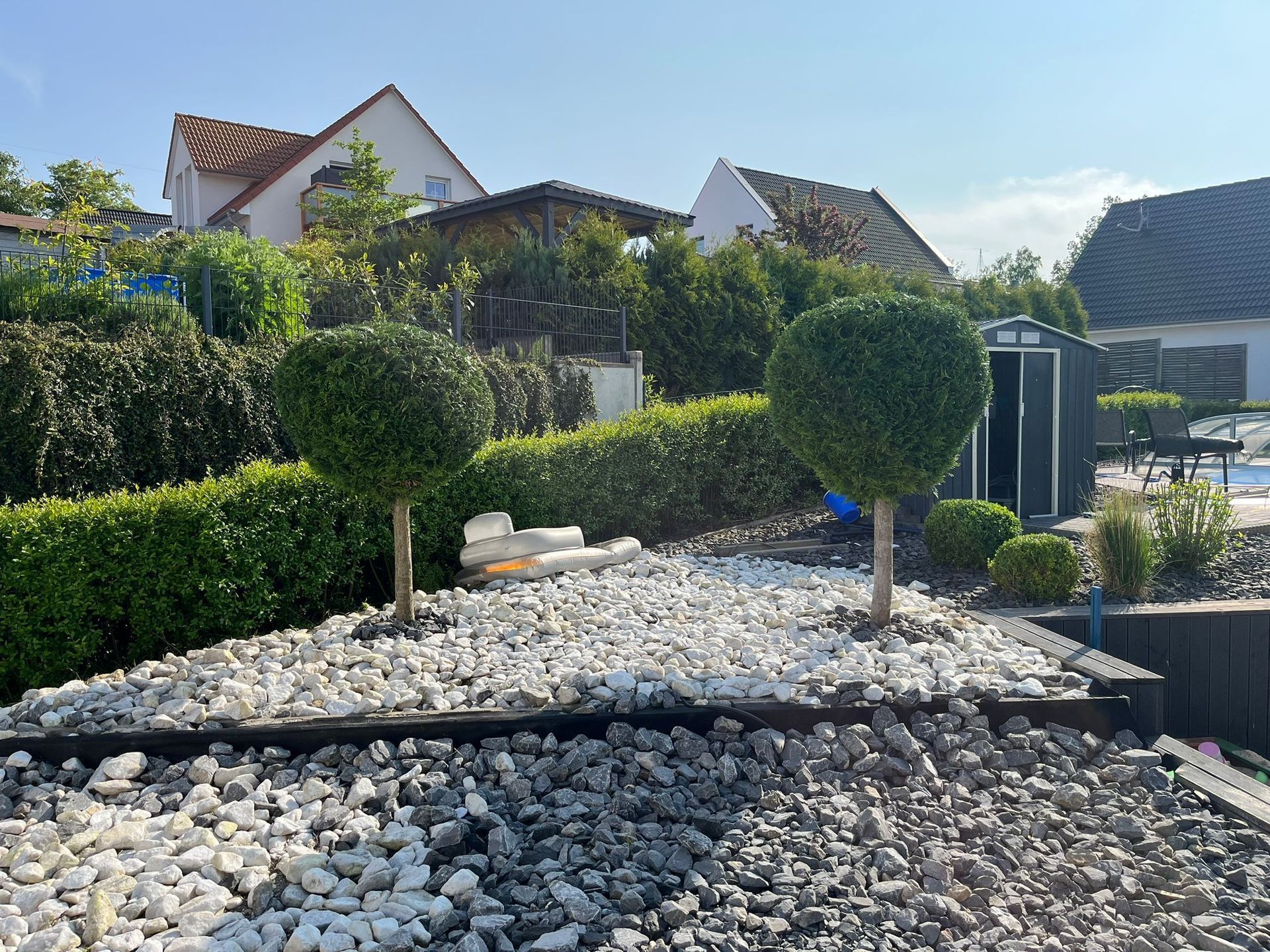 Ein Garten mit vielen Steinen und Bäumen vor einem Haus.