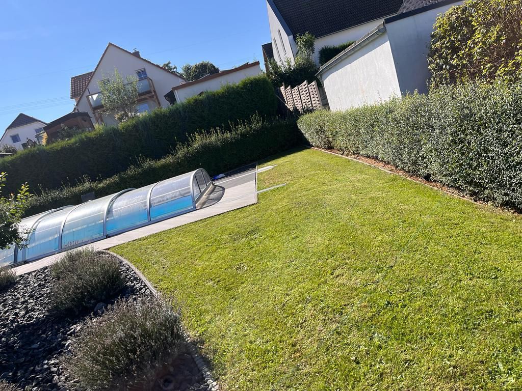 Ein Swimmingpool ist von einem üppigen grünen Rasen umgeben.