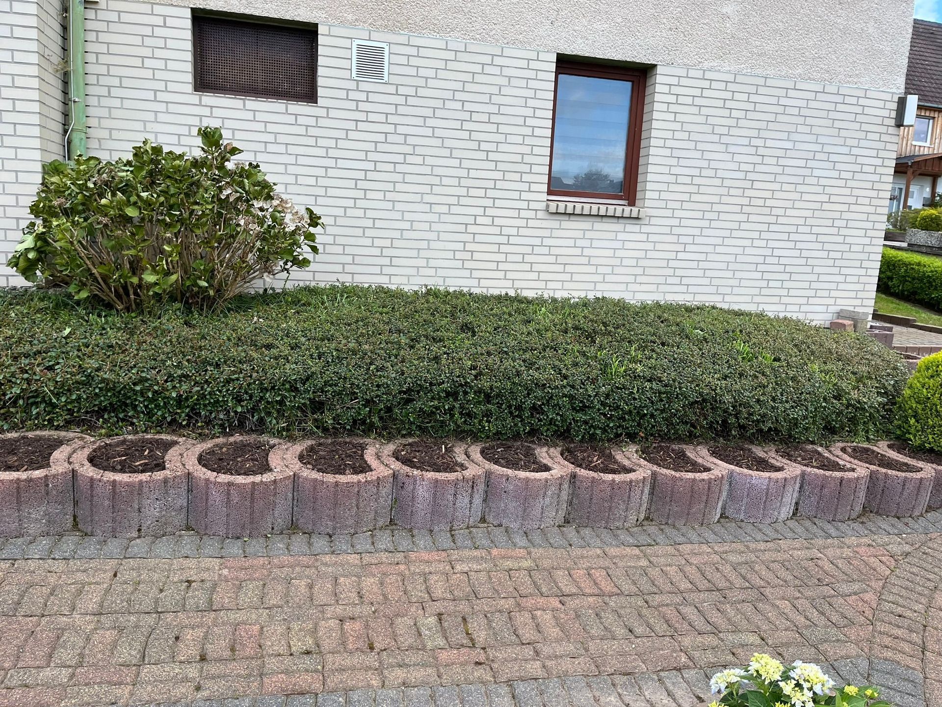 Ein weißes Backsteinhaus mit einem Garten davor.