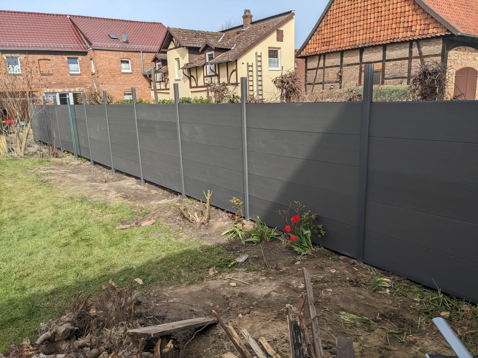 Im Hinterhof vor einem Haus wird ein Zaun gebaut.