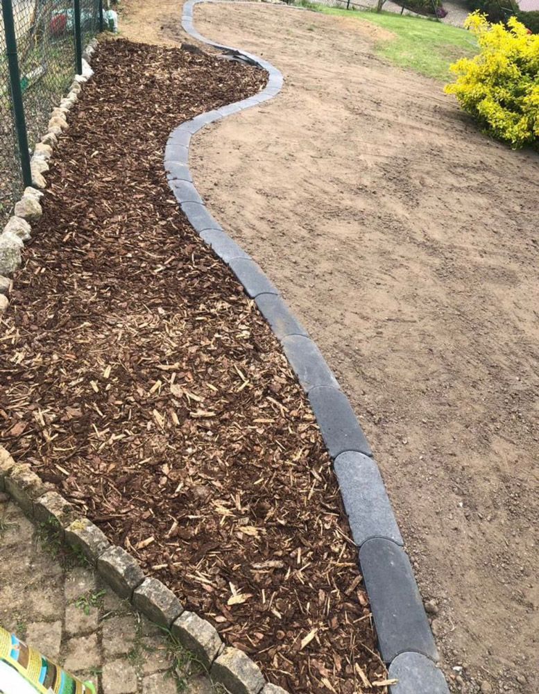 Ein von Mulch und Steinen umgebener Weg in einem Garten.