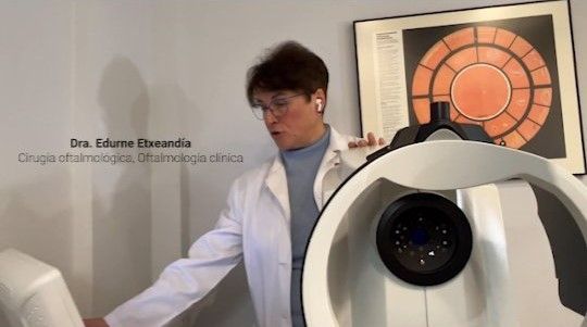 Una mujer con bata de laboratorio está parada frente a una máquina.