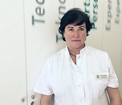 Una mujer con un uniforme blanco está parada frente a una pared con palabras escritas en ella.