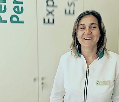 Una mujer con una chaqueta blanca sonríe delante de un cartel que dice experiencia