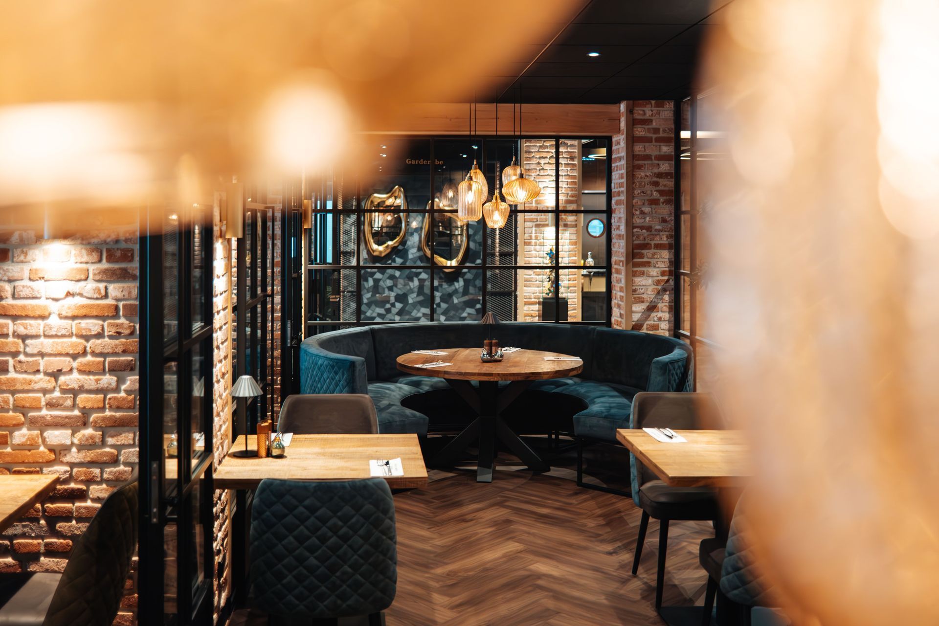 Gezellig restaurantinterieur met blauwe zitplaatsen, bakstenen muren en houten accenten.