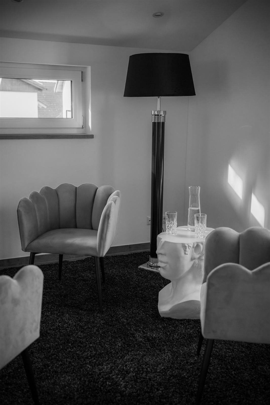 Ein Schwarzweißfoto eines Wohnzimmers mit Stühlen und einer Lampe.