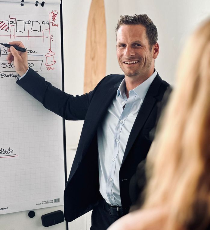Sandro Niederberger von Unternehmerglück steht neben einem Flipchart. Er präsentiert im Rahmen eines Resilienztrainings für Unternehmer wichtige Methoden.