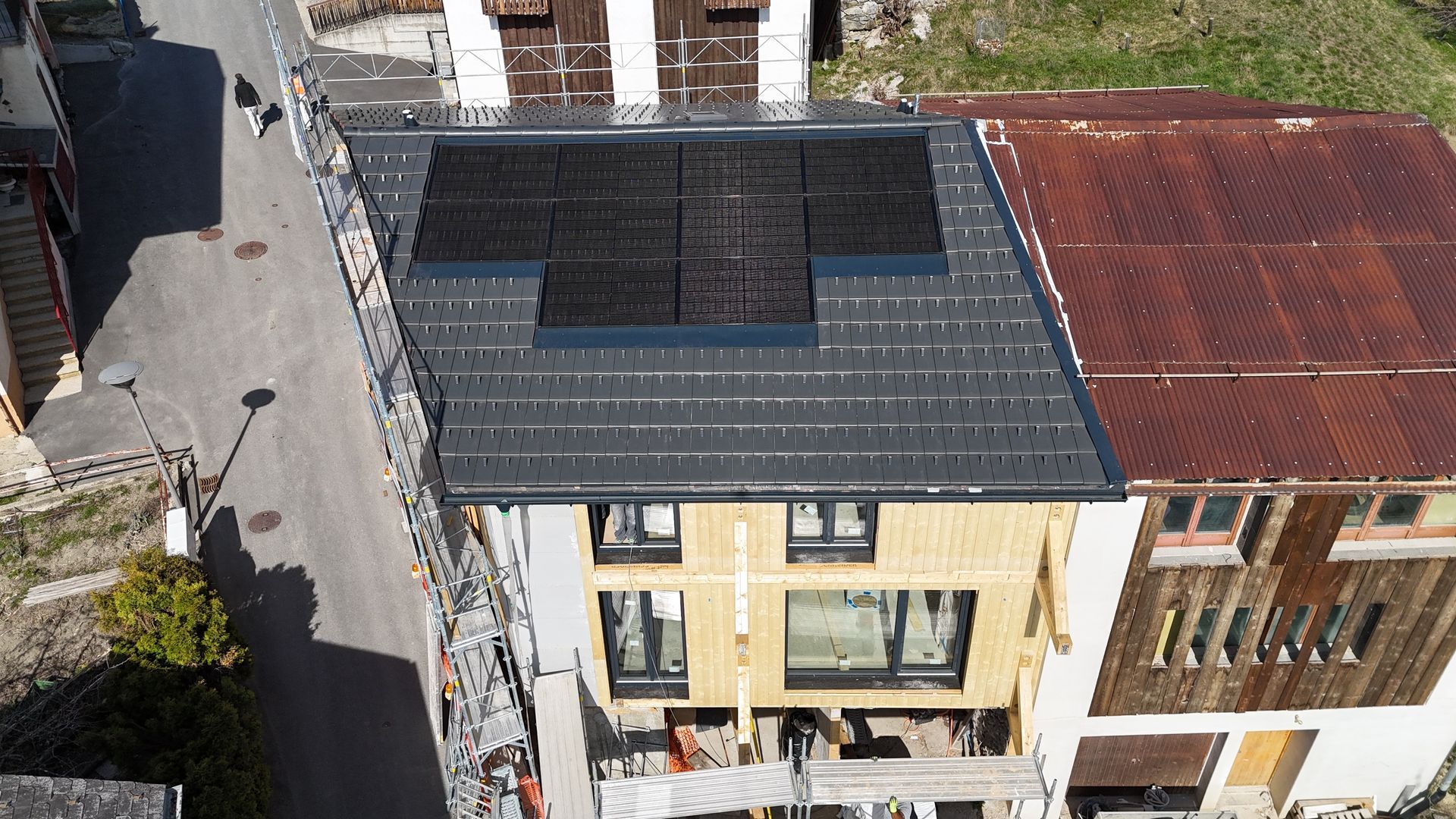 Une personne portant des gants jaunes installe une tuile rouge sur un toit.