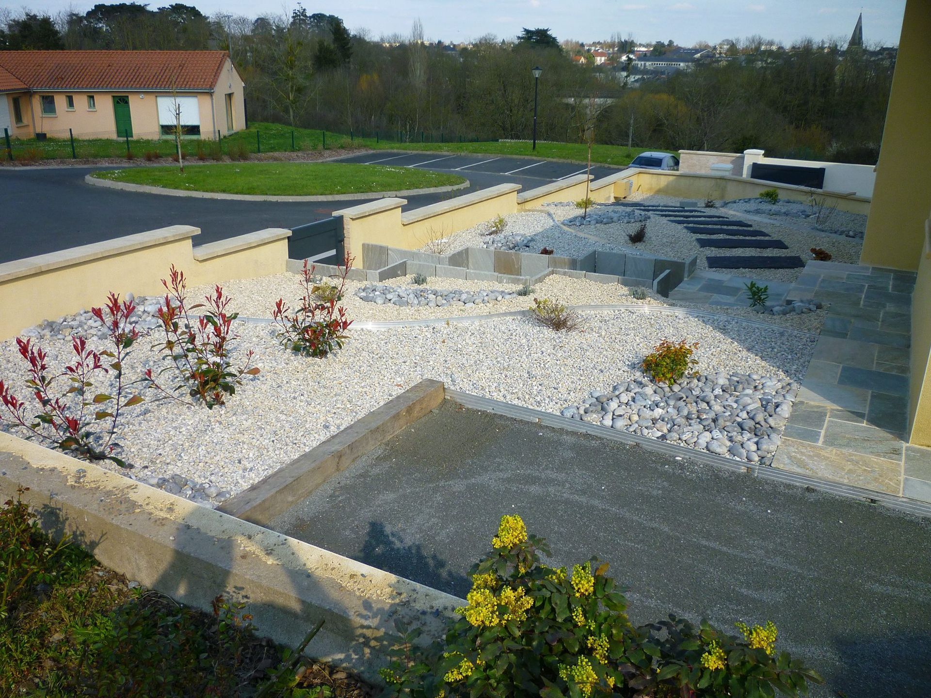 Aménagement devant une maison avec des graviers et plantes