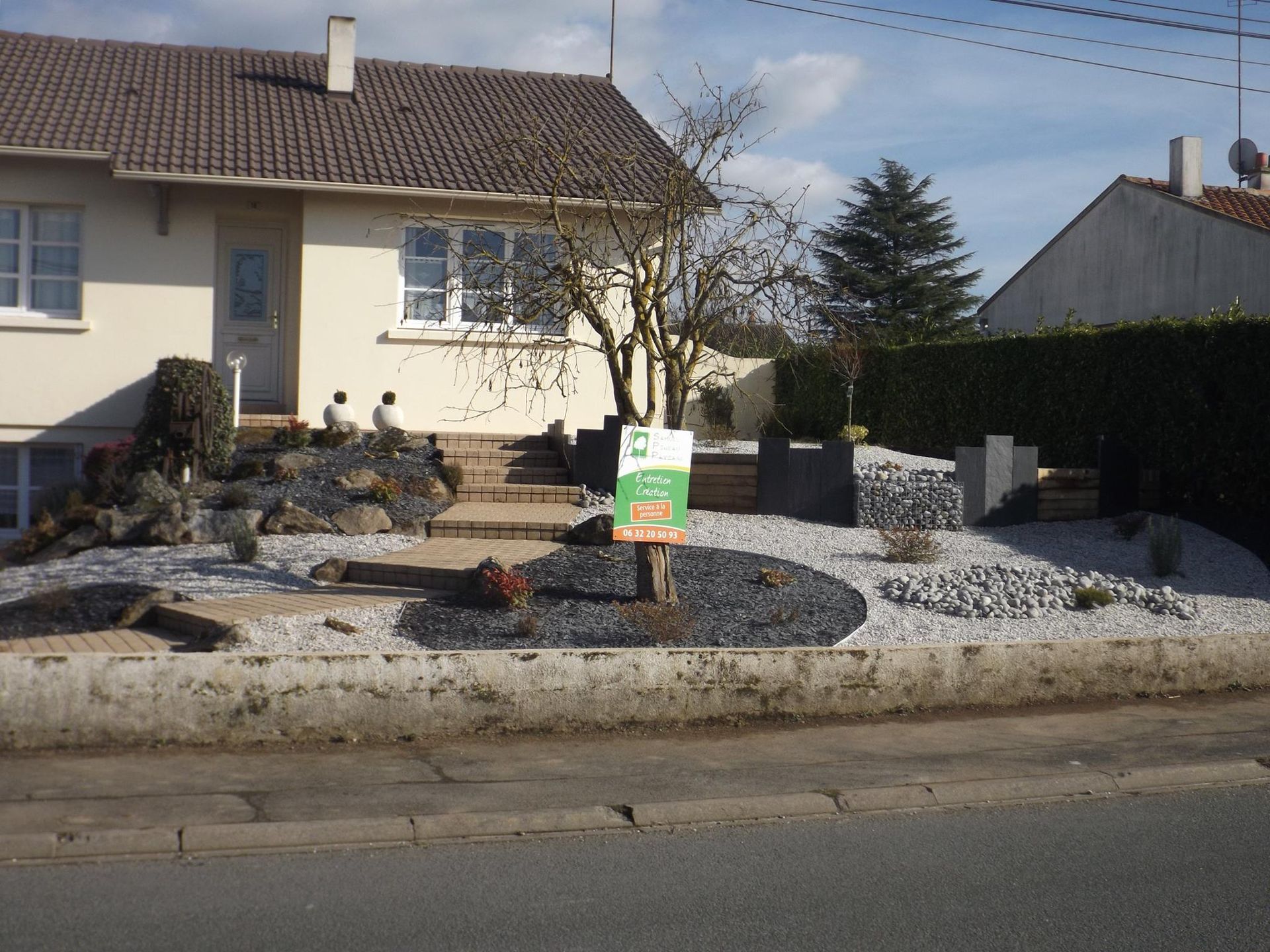 Aménagement paysager avec plantations et roches sur l'avant de maison