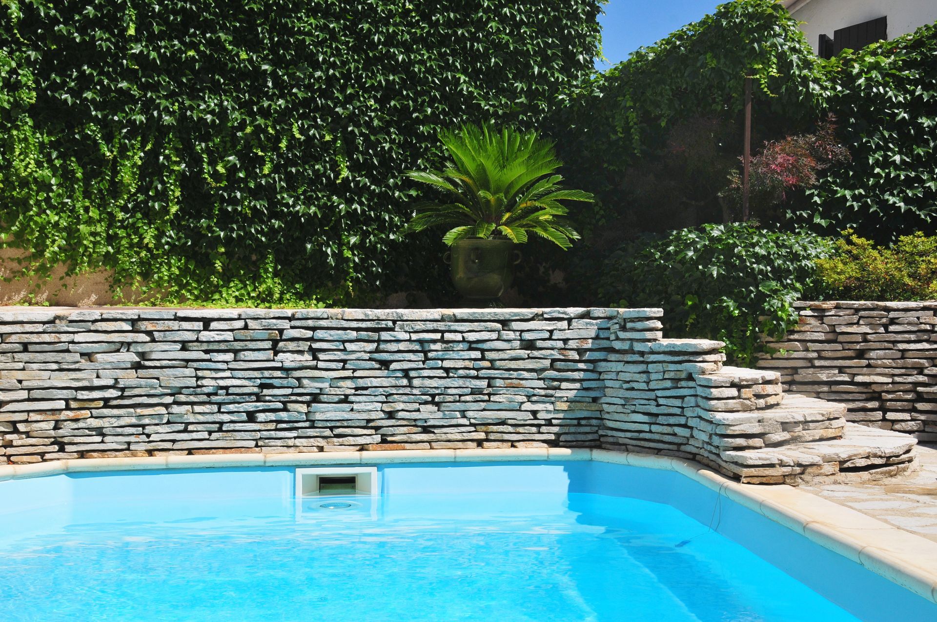 Piscine avec muret en pierre sur le pourtour