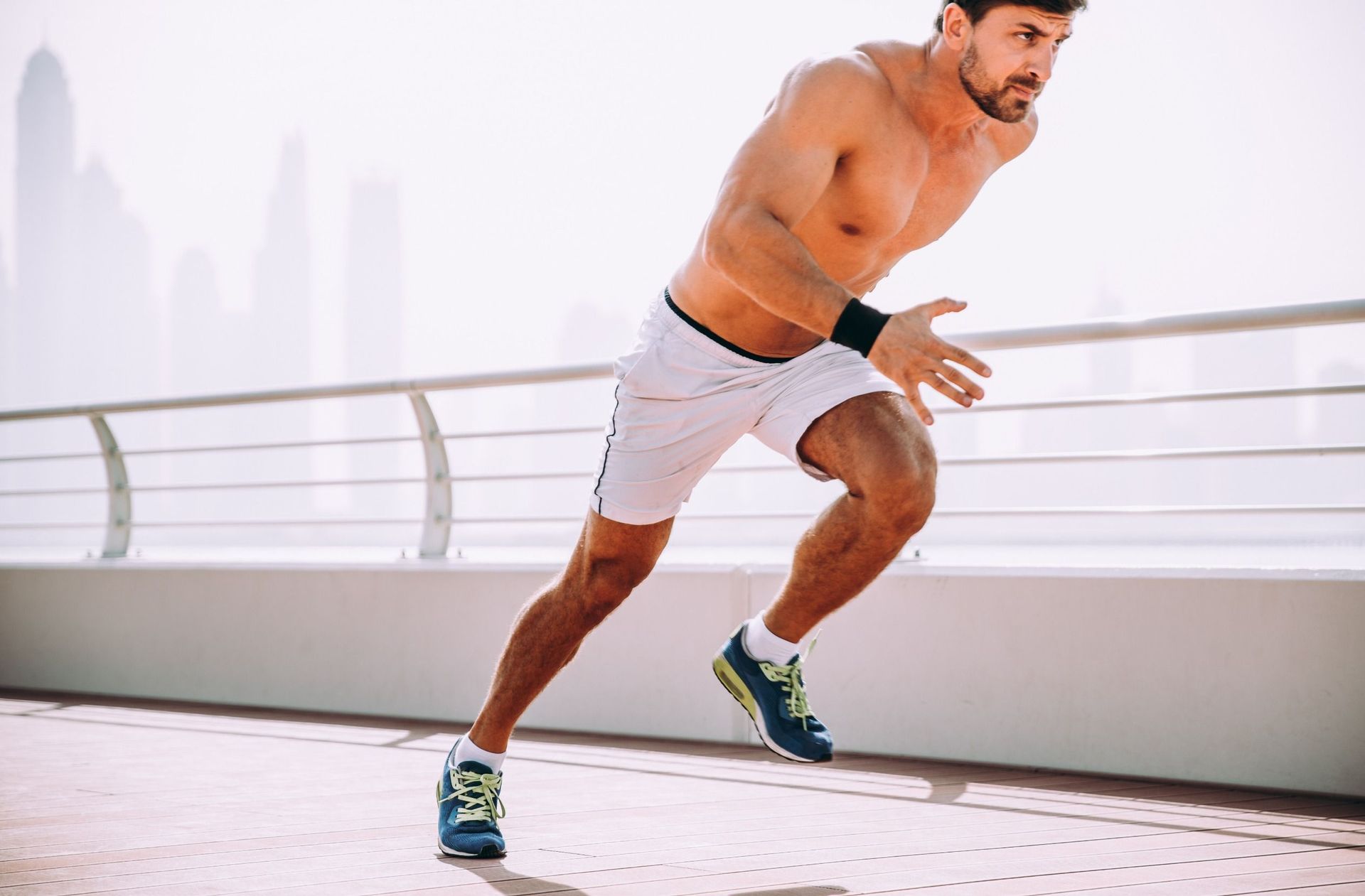 Un hombre sin camisa corre por un puente.