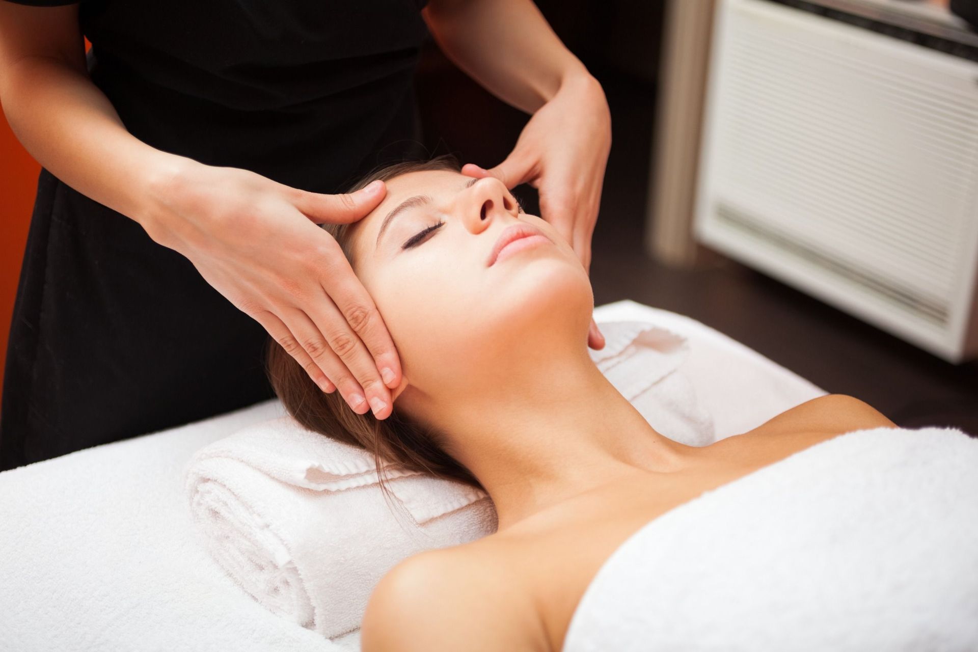 Una mujer está recibiendo un masaje facial en un spa.