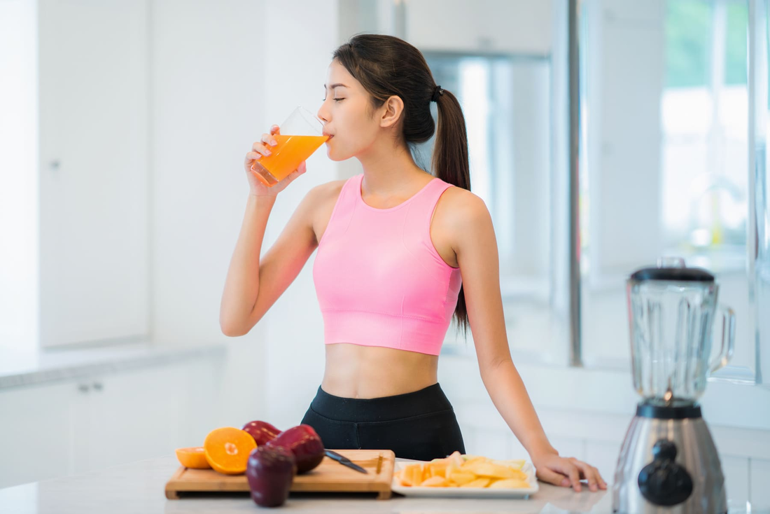 Una mujer está bebiendo jugo de naranja en una cocina.