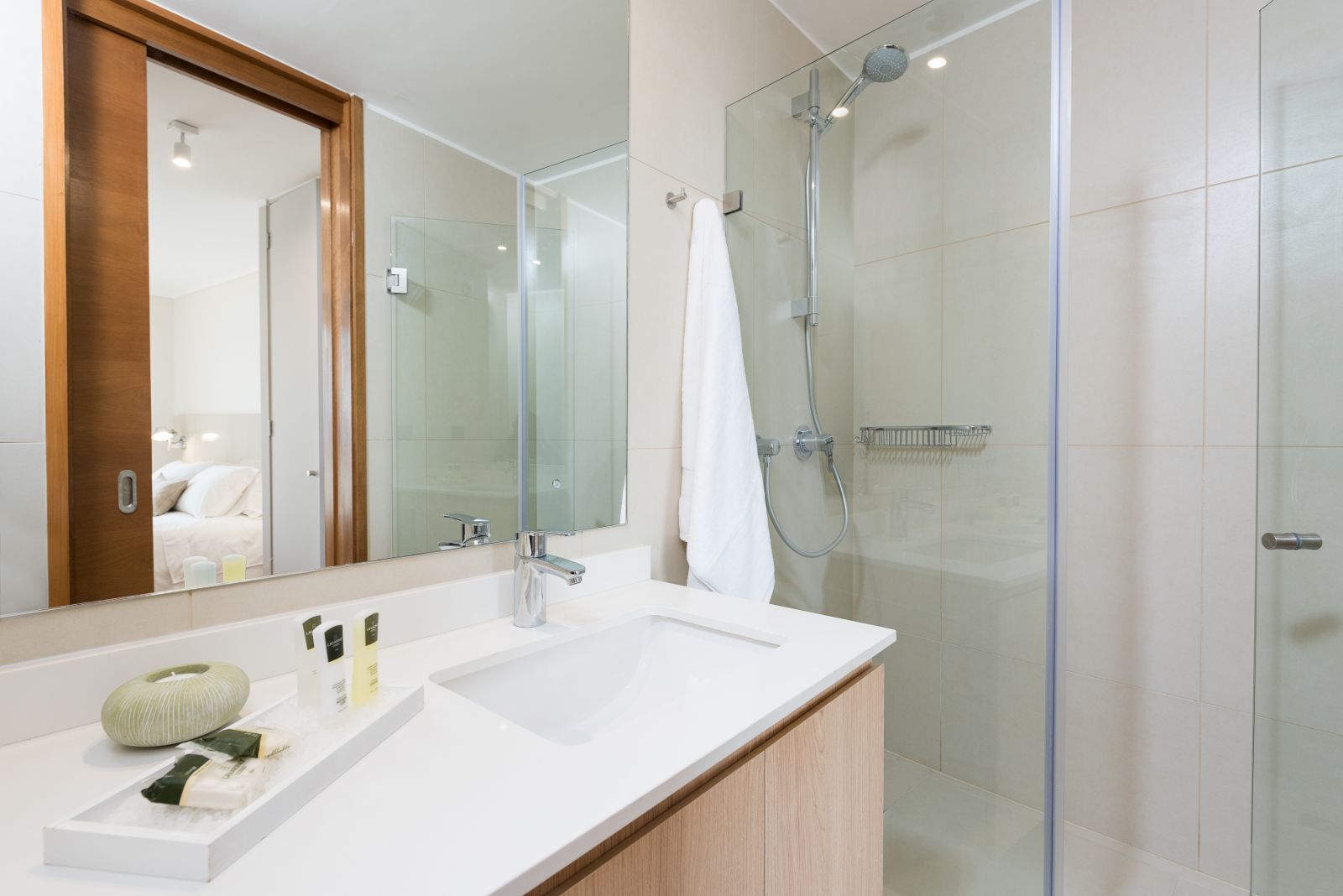 Modern bathroom with white vanity, large mirror, glass shower, and towel rack