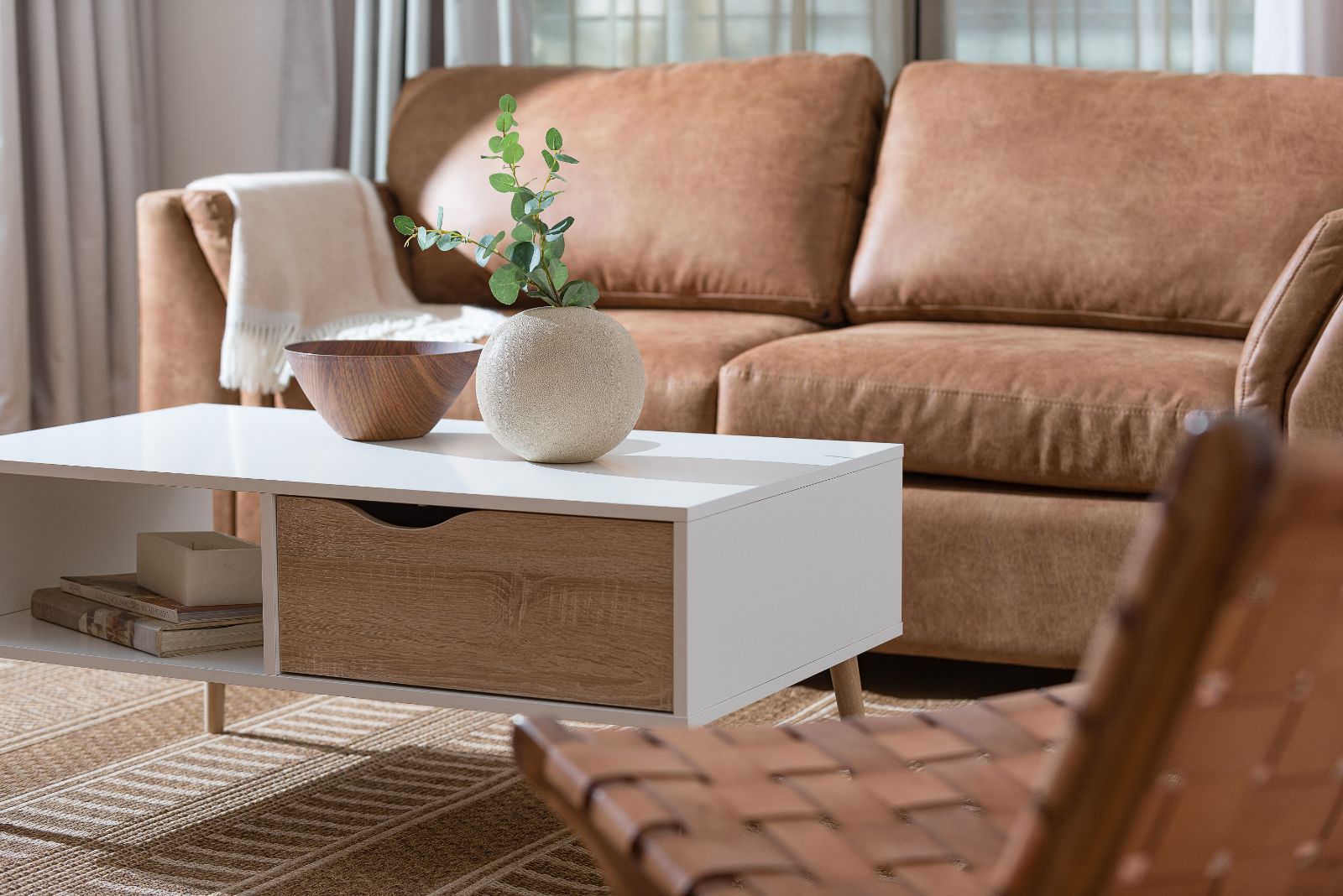 Cozy living room with tan sofa, white coffee table, woven decor, and a wicker chair