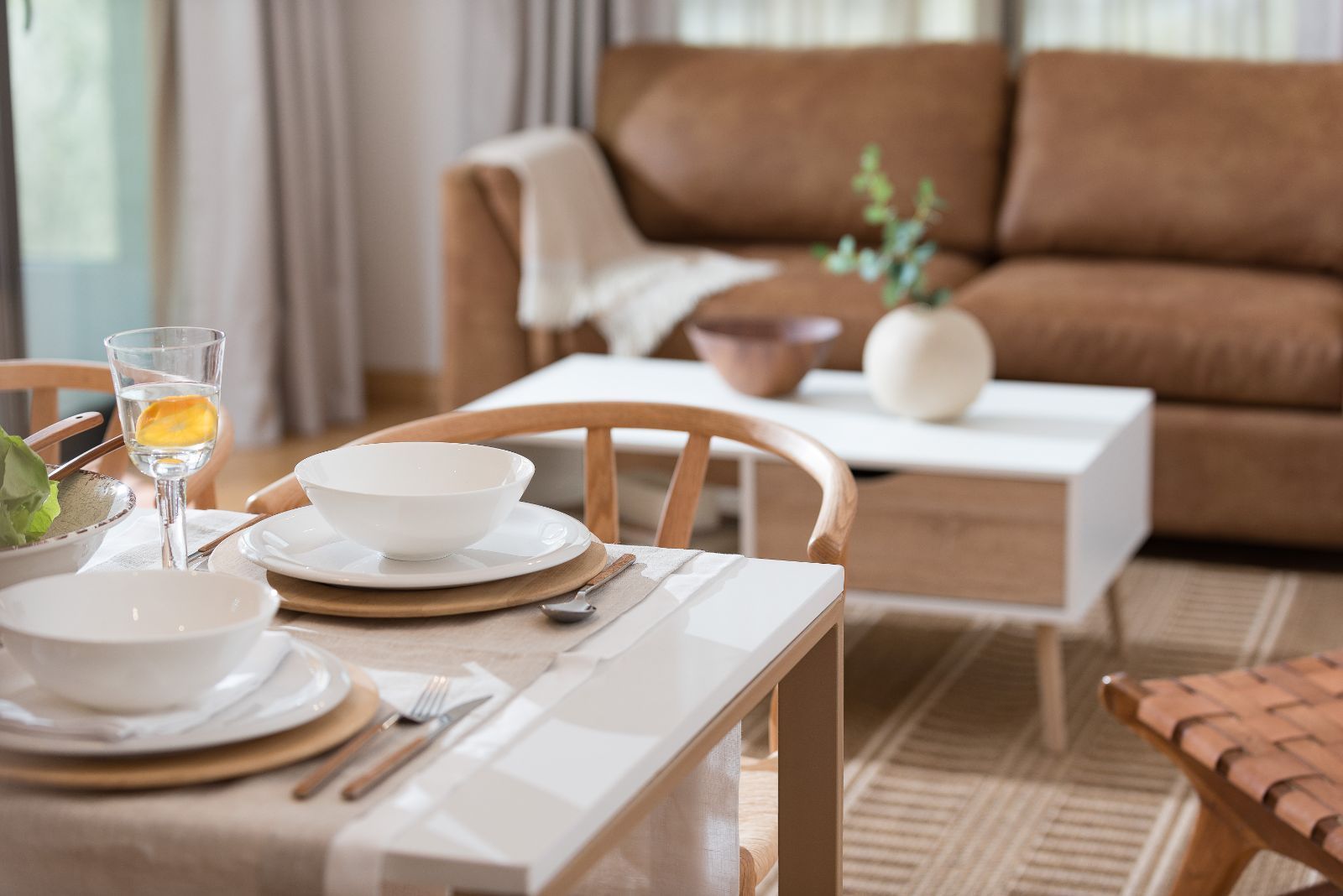 Cozy living room with a set dining table, sofa, coffee table, and natural light.