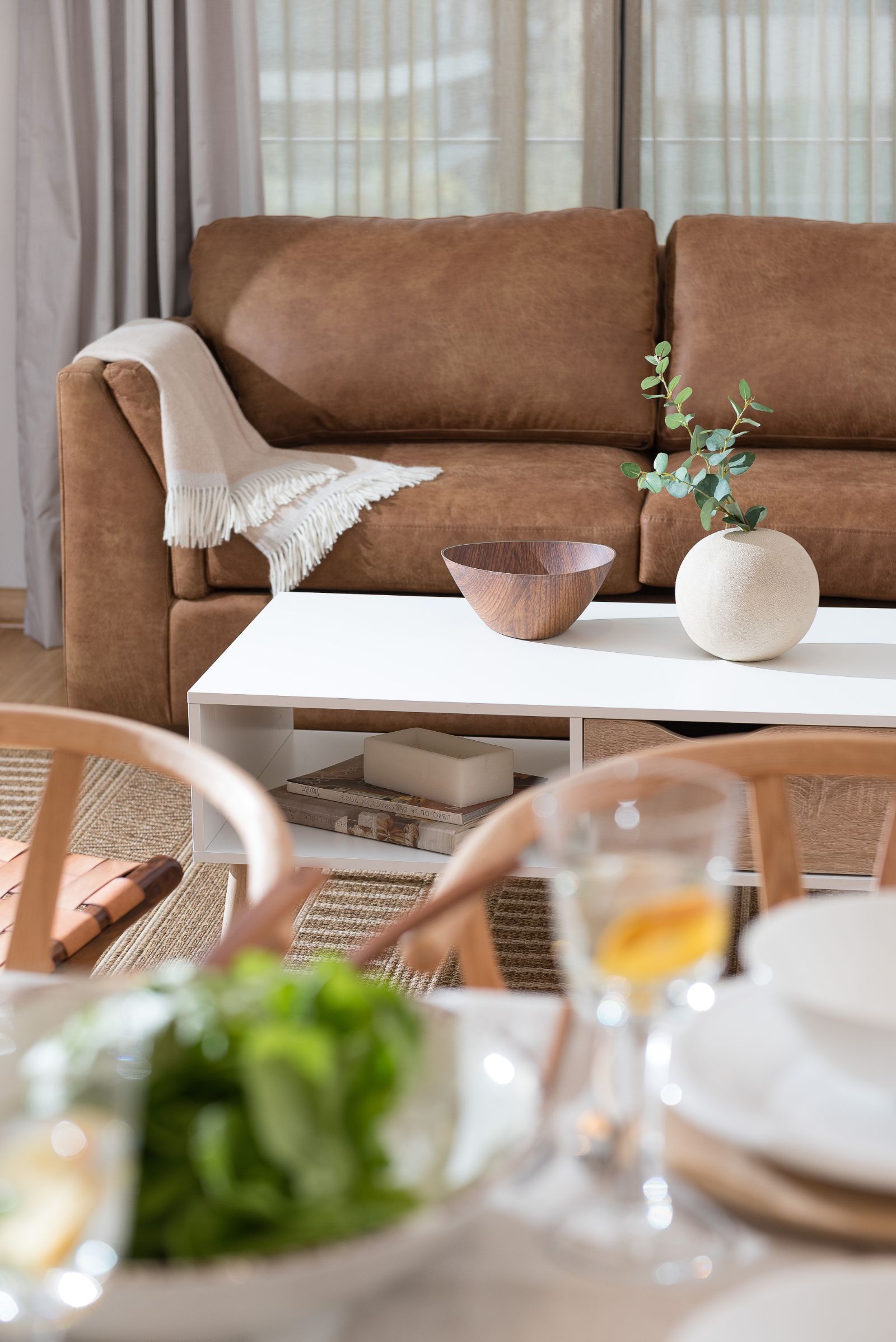 Cozy living room with brown sofa, white coffee table, and soft neutral decor