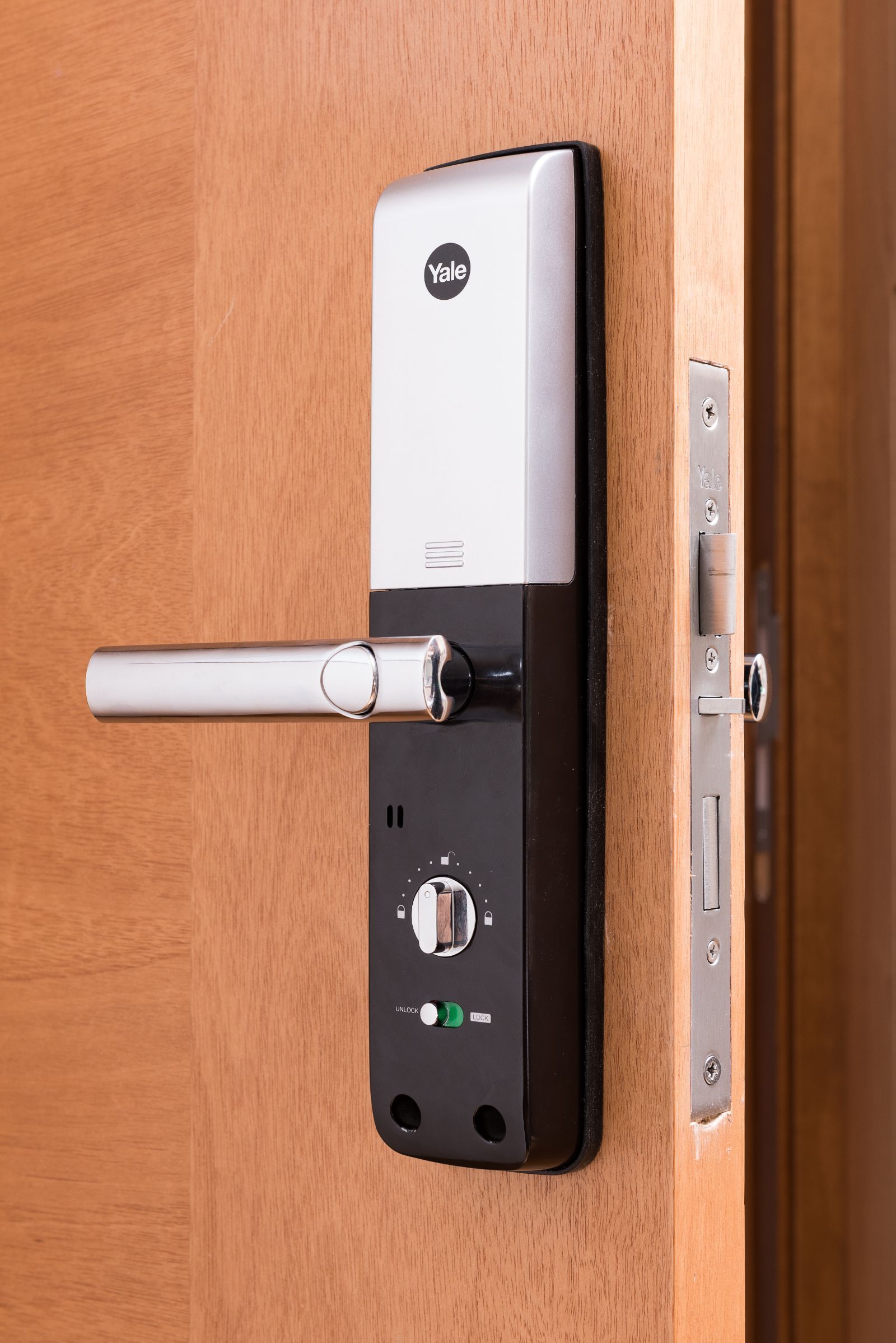 Modern silver and black door lock with handle on a wooden door