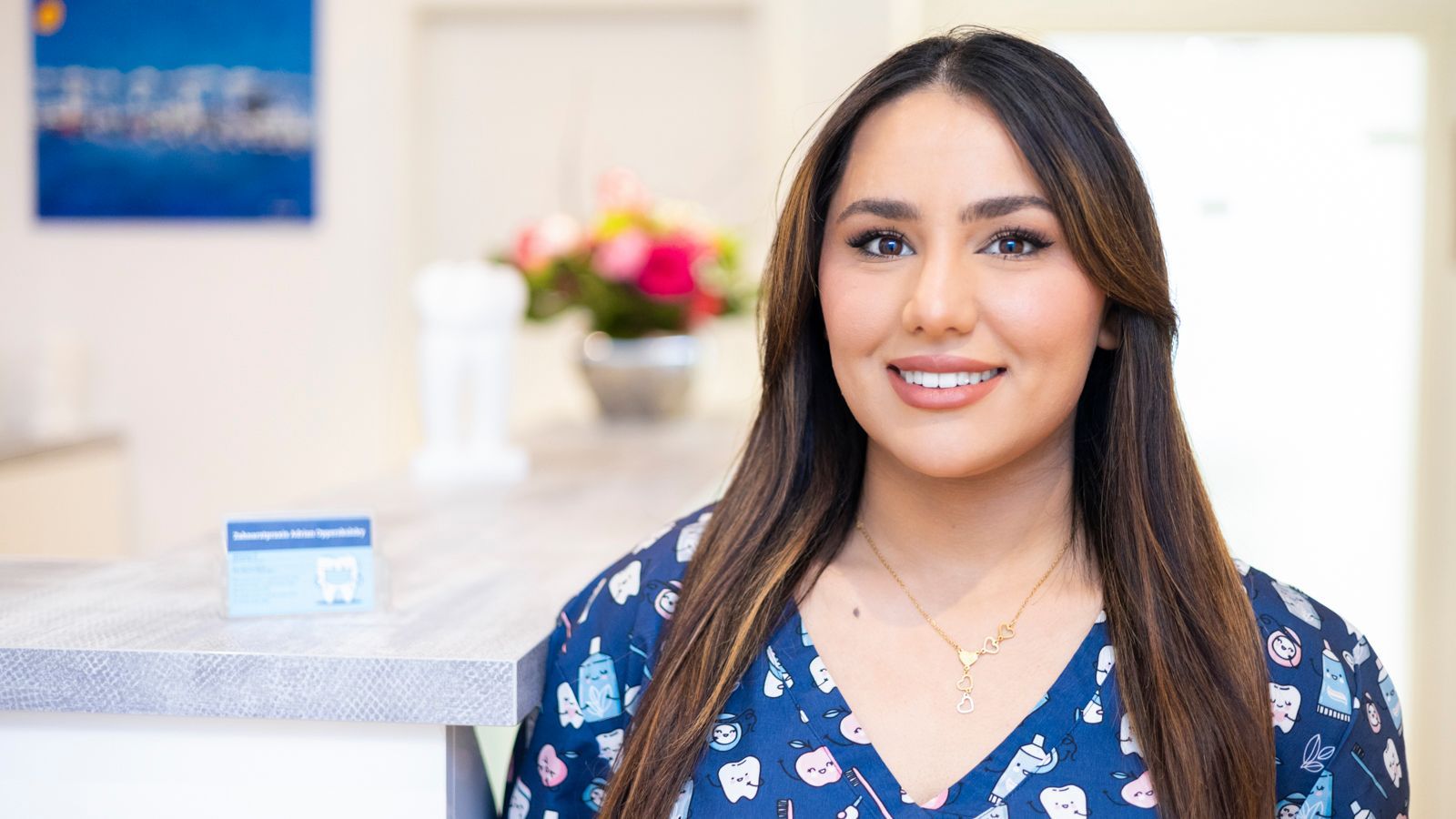 Eine Frau in einem blauen OP-Kittel lächelt in die Kamera.