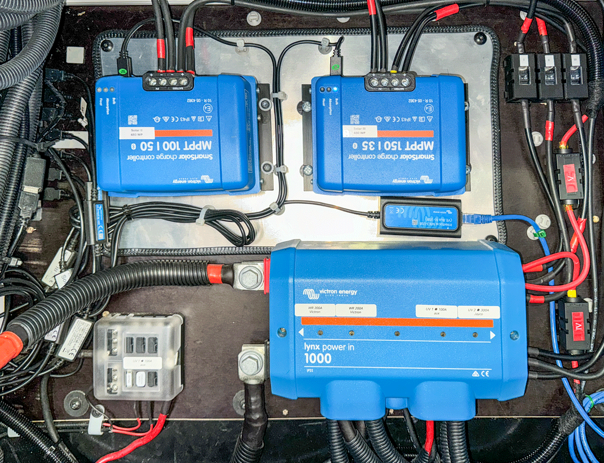 Blaue Solarladeregler und Wechselrichter, auf einem Panel mit Verkabelung montiert.