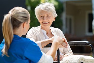 ne jüngere und eine alte Frau unterhalten sich freundlich auf einer Couch.