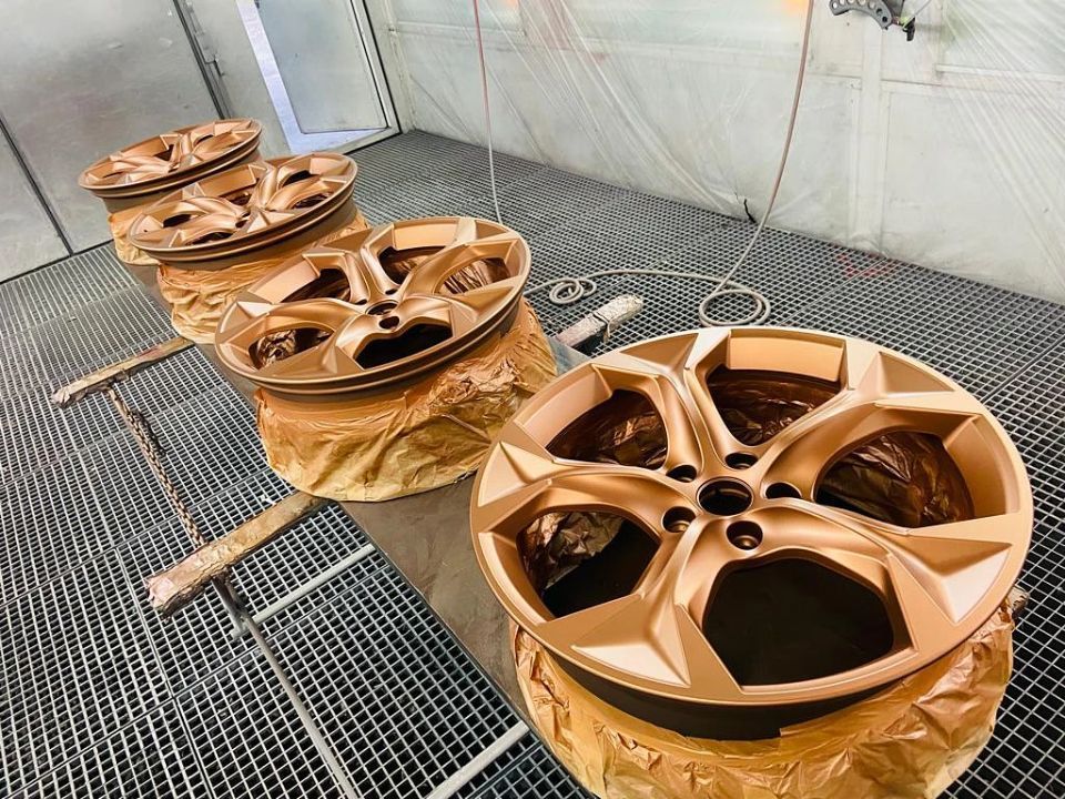 In einer Lackierkabine liegt eine Reihe Räder nebeneinander.