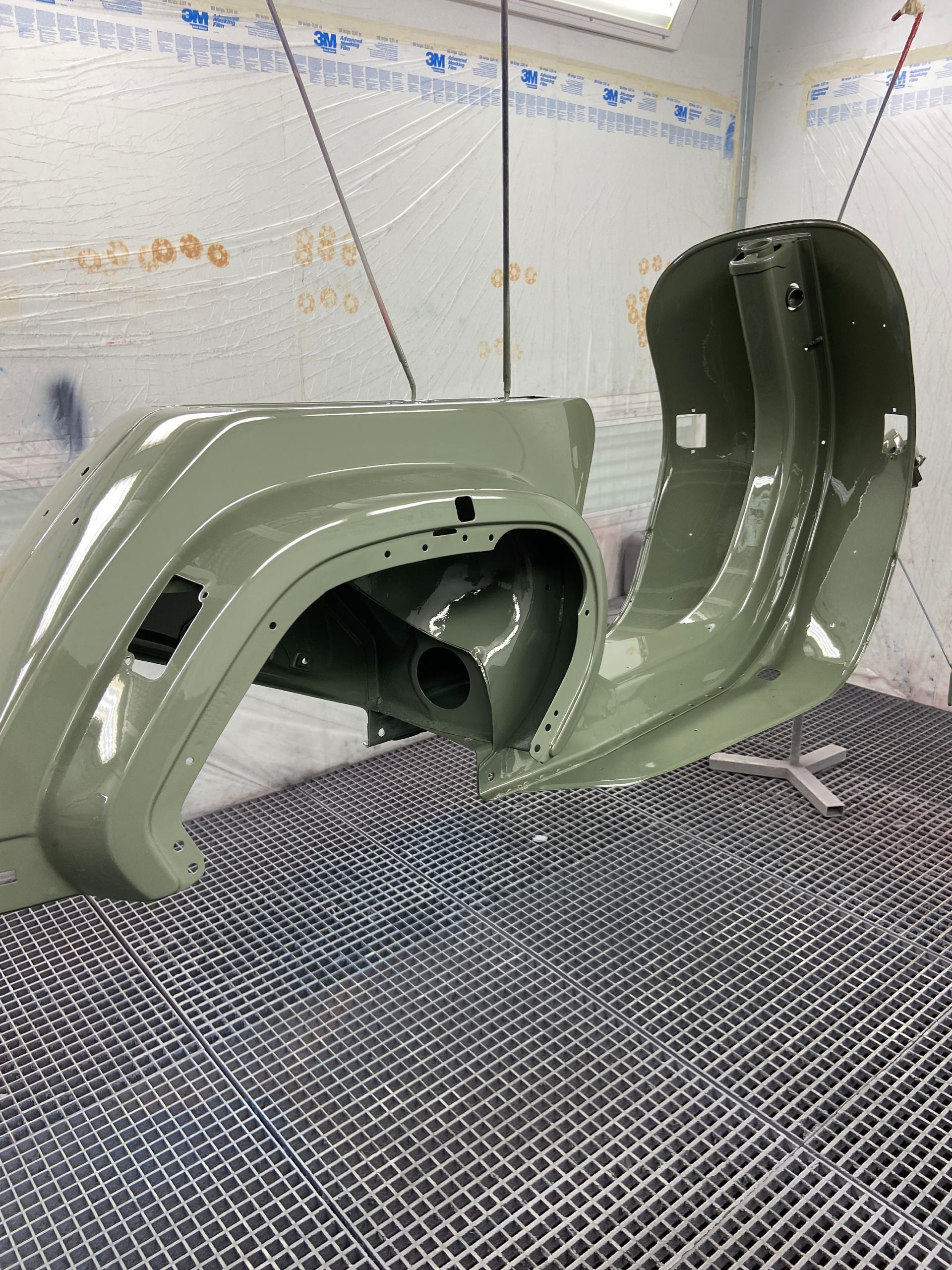 Ein Roller wird in einer Lackierkabine grün lackiert.