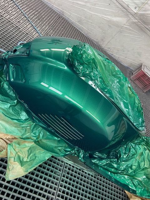 Ein grünes Motorrad ist in Plastik eingewickelt und wird lackiert.