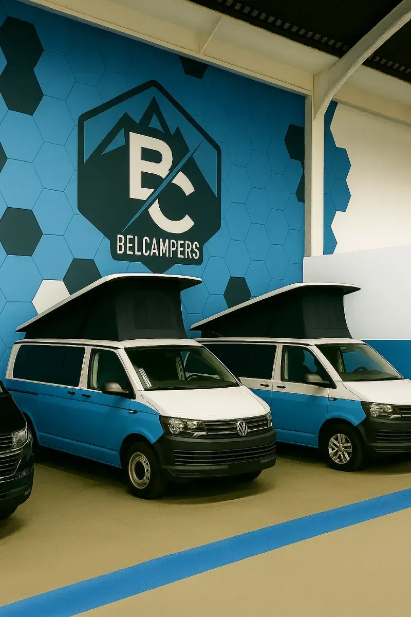 Dos furgonetas camper azules y blancas aparcadas en una sala de exposición con el logotipo