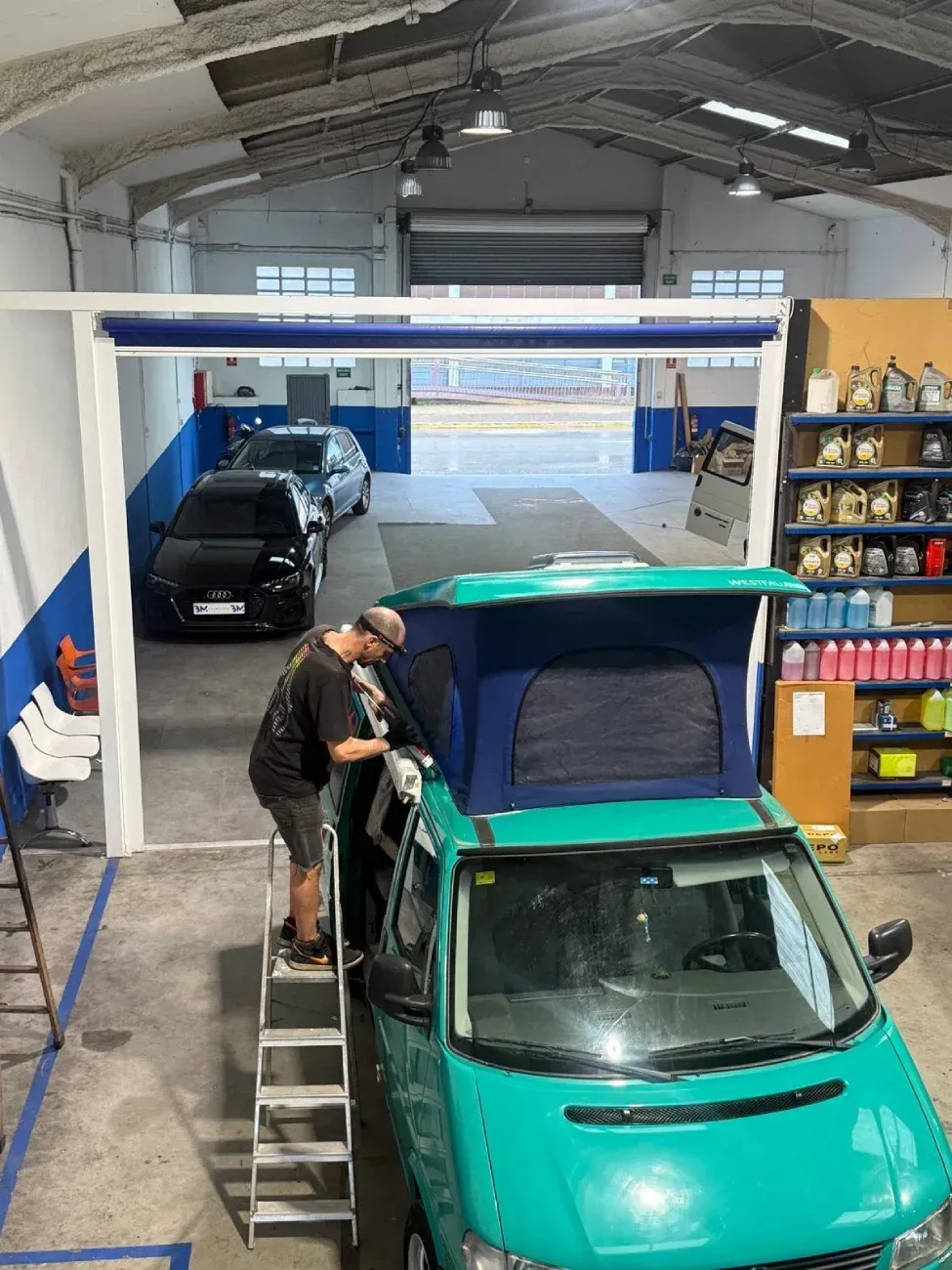 Un hombre subido a una escalera limpia una furgoneta camper