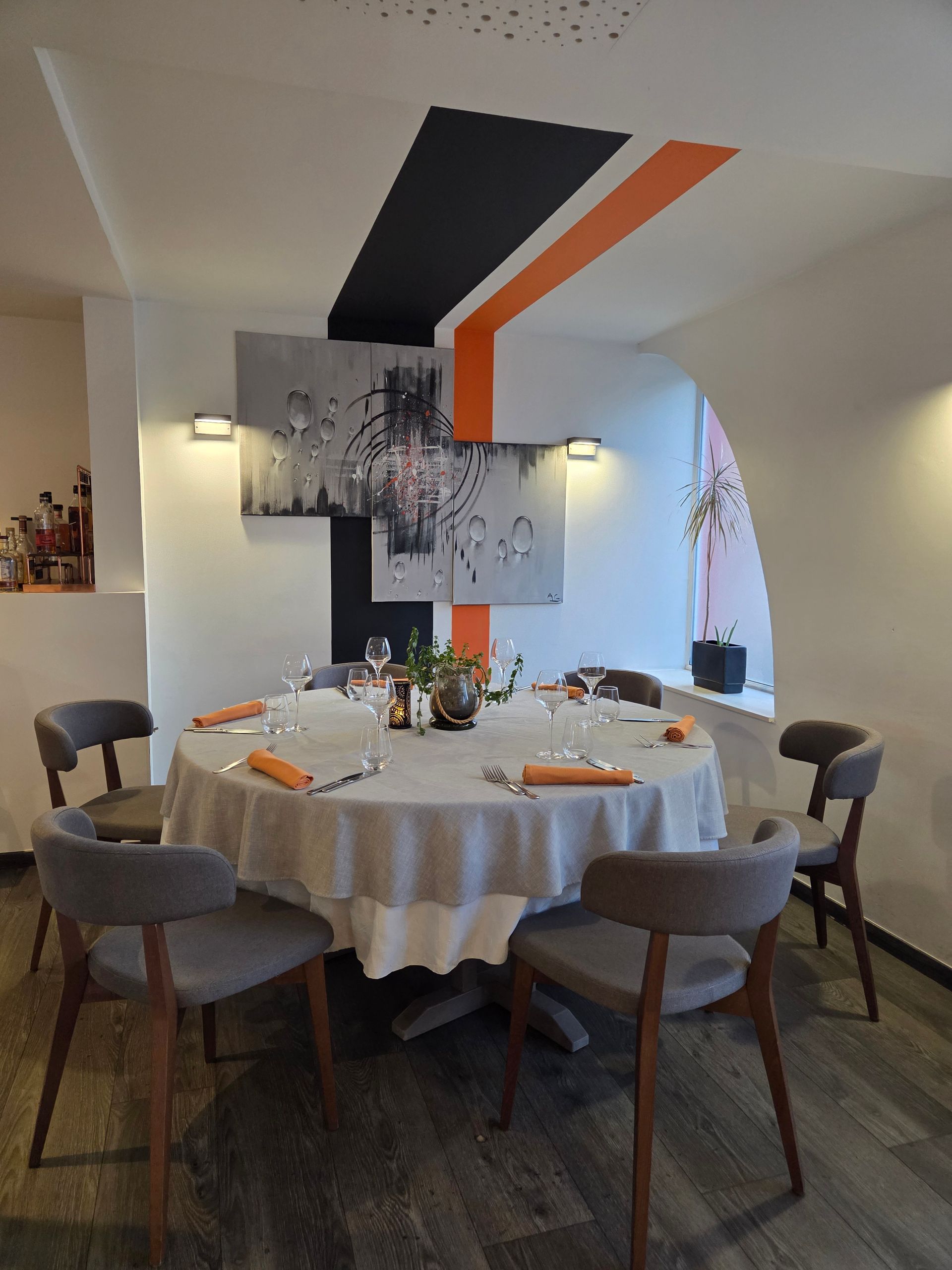 Une table ronde dressée pour dîner avec des chaises grises dans un restaurant.