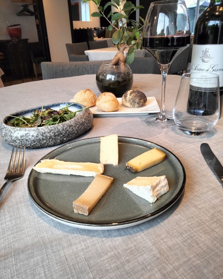 Une assiette de tranches de fromage assorties servie sur une table avec du pain.