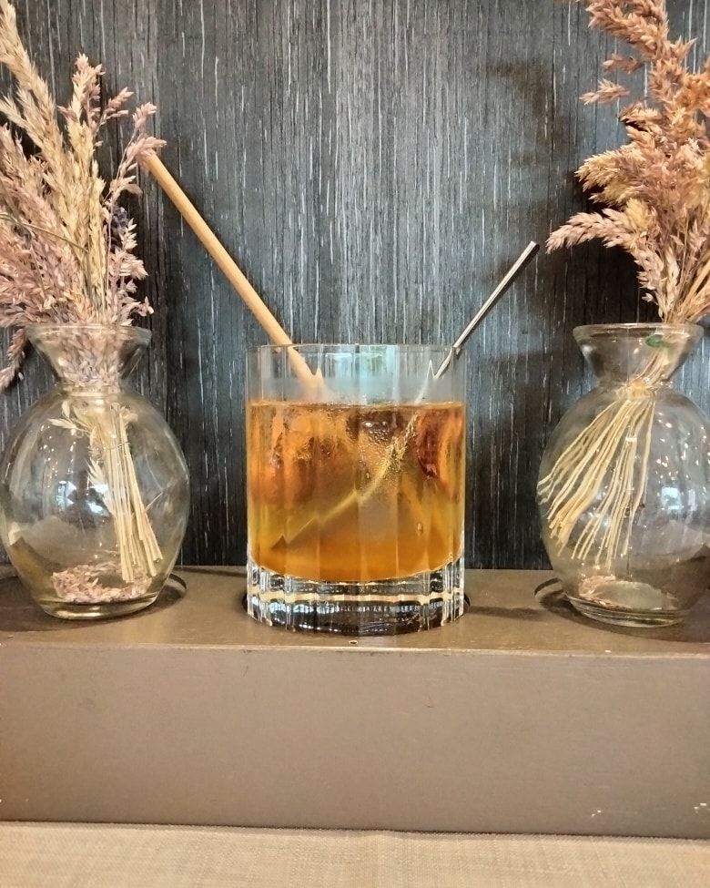 Un verre à cocktail, accompagné d'une paille en bois et d'un agitateur.