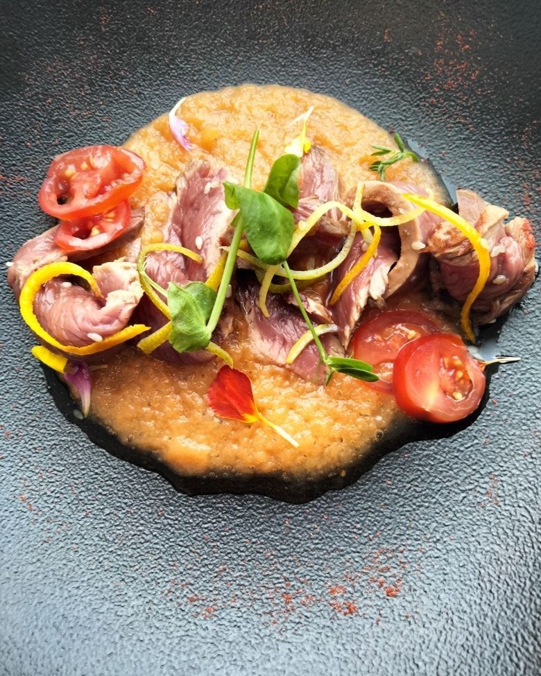 Tranches de viande saisies servies sur une purée d'orange texturée.