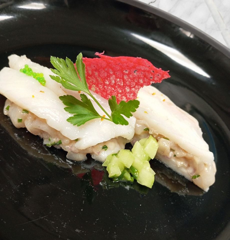 Un plat délicat composé de tranches de poisson blanc cru, garnies d'un brin de persil.