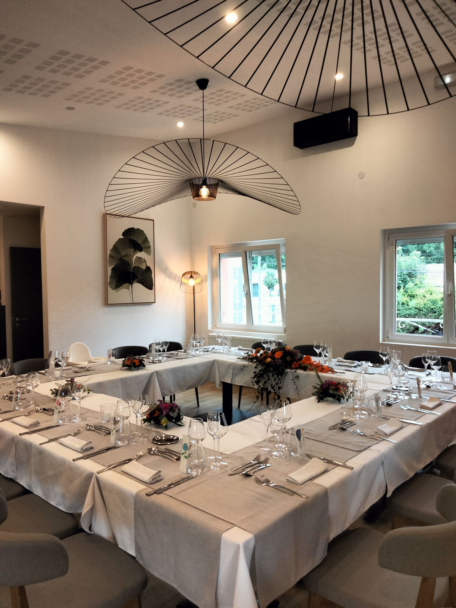 Une table à manger en forme de U dressée pour un événement formel dans une pièce moderne.