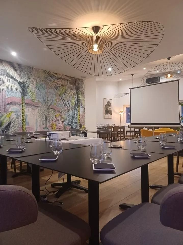 Une salle de réunion dans le restaurant avec des tables sombres disposées pour une conférence.
