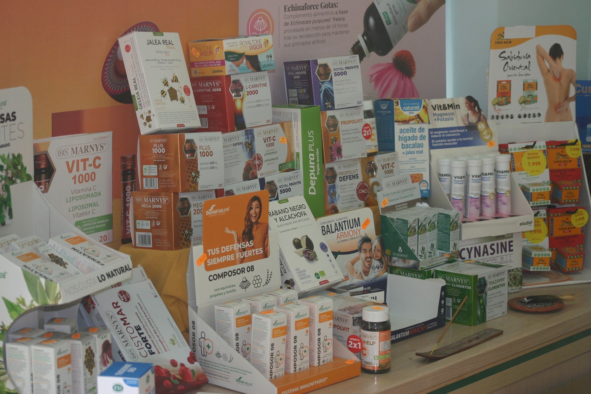 Mesa repleta de cajas y frascos de vitaminas y suplementos variados en un estante de la tienda.