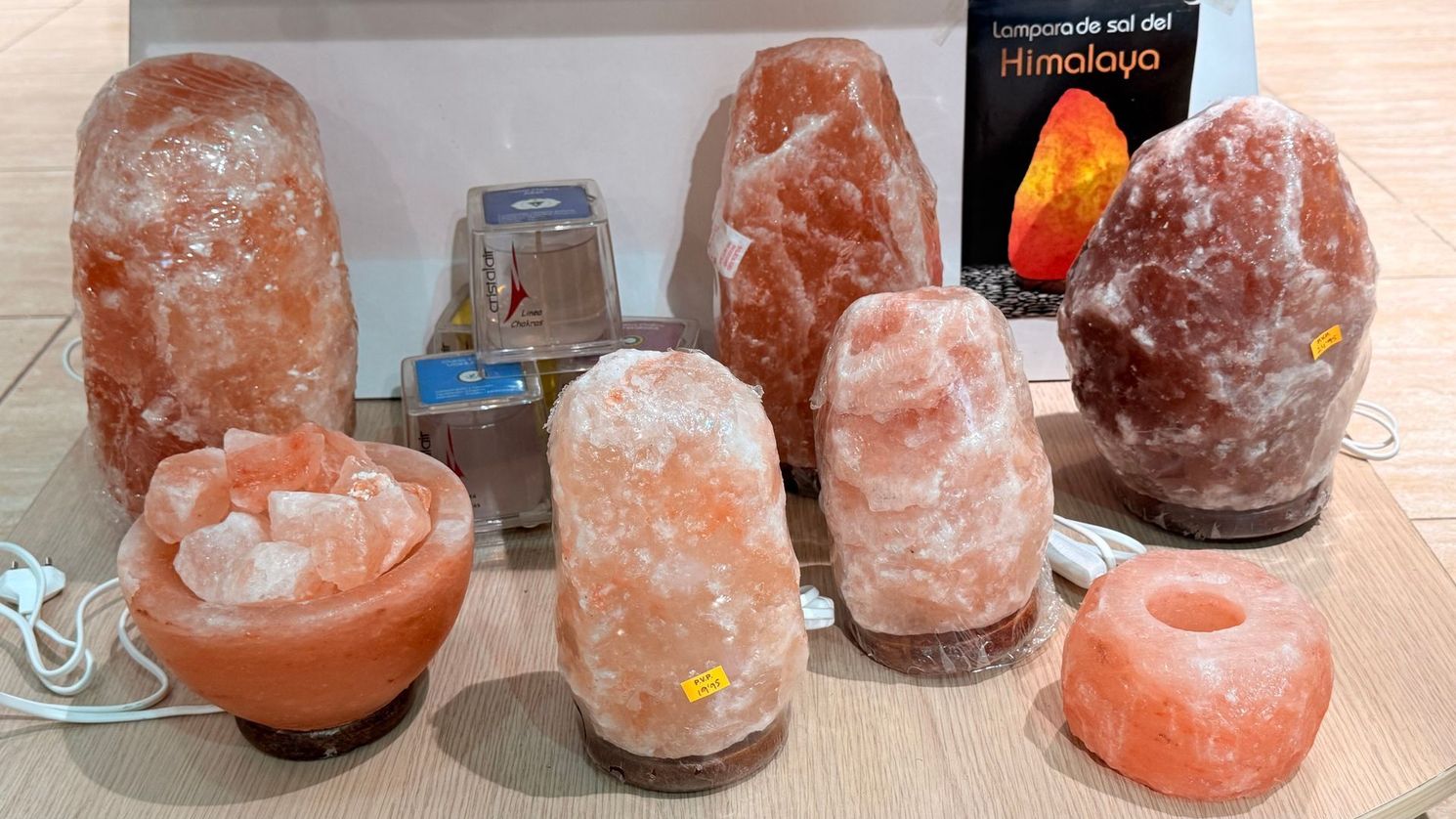 Exhibición de lámparas y portavelas de sal del Himalaya de color rosa anaranjado sobre una mesa.