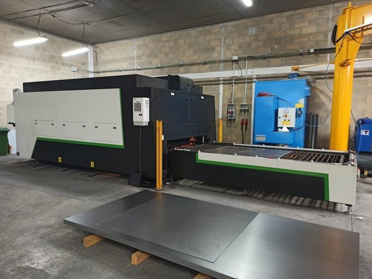 Una máquina está en un almacén al lado de una gran pieza de metal.