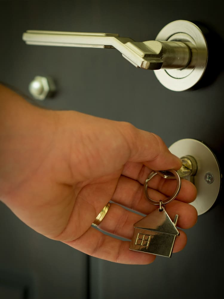 Una mano sostiene una llave con un llavero de casa adjunto.