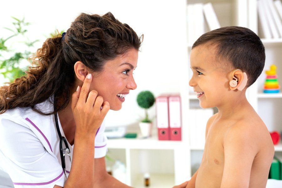 Une dame aide un enfant avec une prothèse auditive contour d'oreille